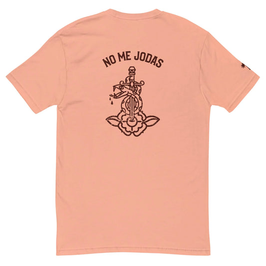 The No Me Jodas Fitted Graphic Tee by Printful features a peach hue, soft cotton fabric, and a bold black graphic of a dagger through a flower with the phrase NO ME JODAS above—perfect for fans of standout mens tees.