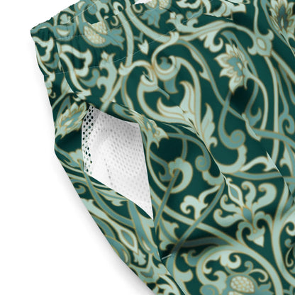 Close-up of Printful Oz Swim Trunks for men, featuring a green and beige floral pattern, white mesh-lined pocket, and elastic waistband. Made from water-repellent, four-way stretch fabric for comfort.