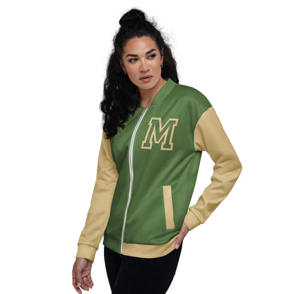 Woman with long curly dark hair wears a green and yellow varsity bomber jacket with an M on the chest, posing with one hand in her pocket against a plain white background.