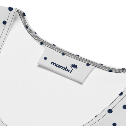 Close-up of the inside neckline of an all-over printed dress with white fabric, navy blue polka dots, and gray stitching. A white tag displays the brand name “mambi” with a palm tree graphic in navy blue.