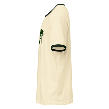 Side view of a beige retro t-shirt with dark green ribbed collar and sleeve cuffs. Made from lightweight cotton, this relaxed fit tee features a small green palm tree and partial green text on the upper chest area.