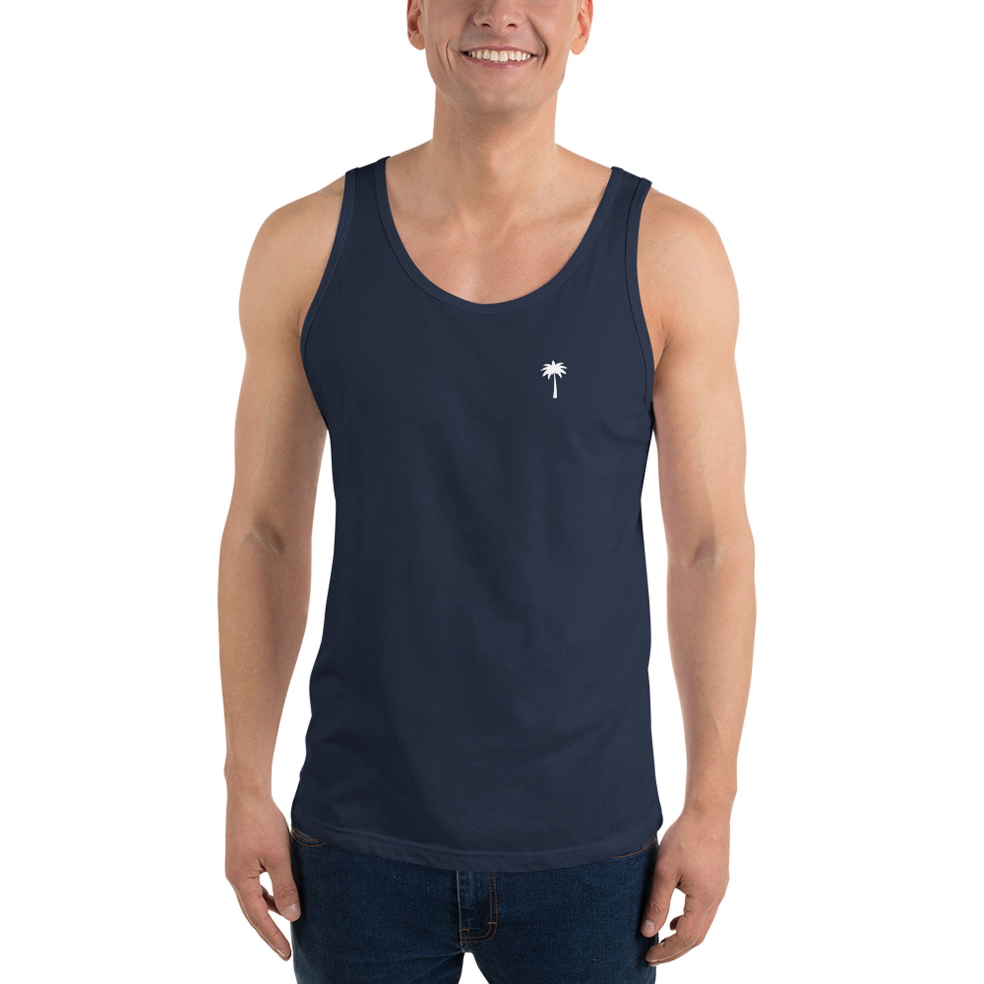 A smiling person wears a classic navy blue tank top made from soft ringspun cotton, featuring a small white palm tree graphic on the left chest, standing against a plain white background.