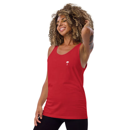 A smiling woman with curly hair wears a classic ringspun cotton tank top in red, featuring a small white palm tree graphic on the left chest, standing against a plain white background.