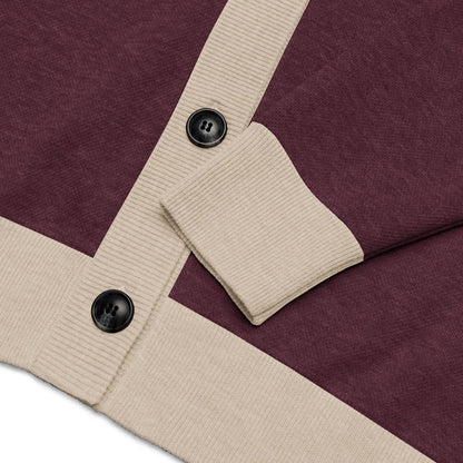 Close-up of a maroon cardigan with ribbed beige trim, featuring two large black buttons and a folded sleeve—this unisex sweater is crafted from a lightweight knit for comfort and versatility.