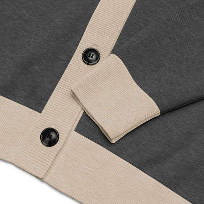 Close-up of a grey two-tone cardigan with beige ribbed cuffs and hem, featuring two large black buttons.