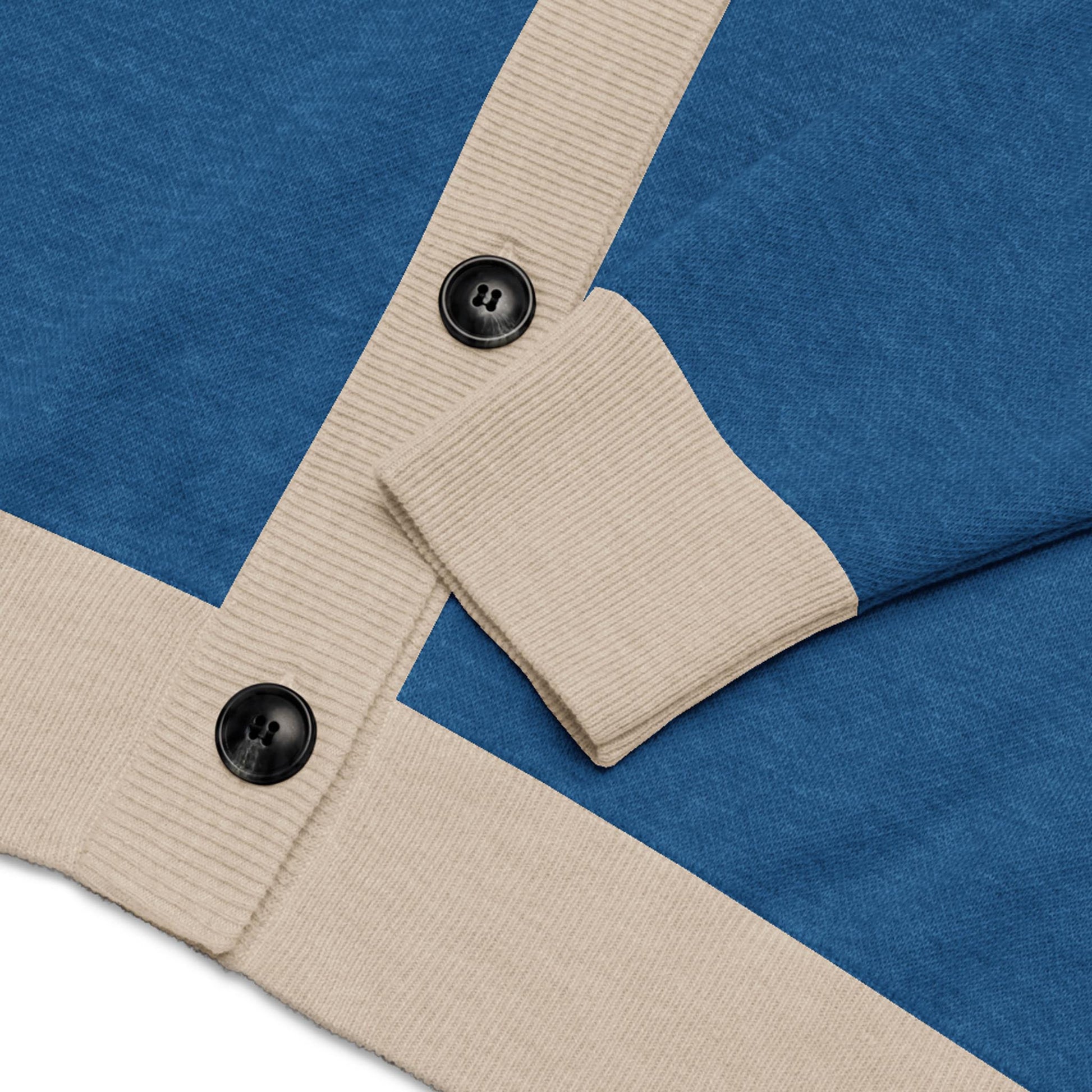 A close-up of a blue jacquard knit garment with cream-colored ribbed cuffs and trim, featuring two black buttons.