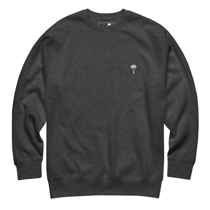 A plain dark gray Mambí crewneck sweatshirt featuring a small white embroidered palm tree on the left chest. The sweatshirt has long sleeves and a relaxed fit.
