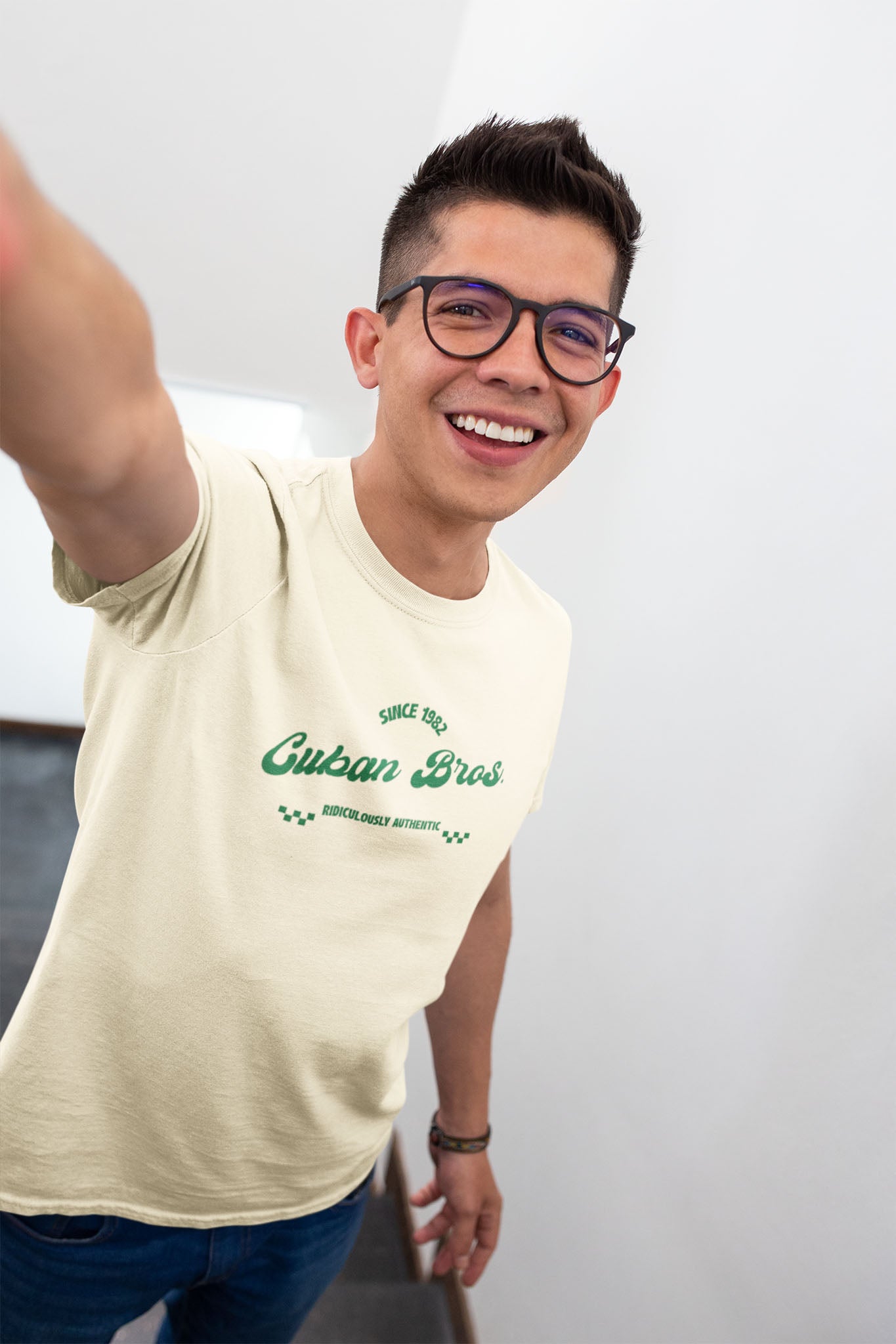 Person wearing a beige t-shirt with green 'cuban bros' logo against a plain background