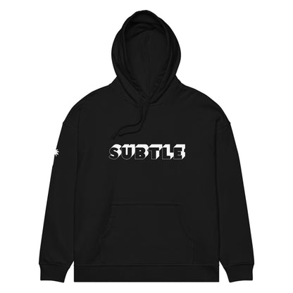 Black hooded sweatshirt featuring Mambí with SUBTLE written in bold, white, uppercase letters across the chest. A small white graphic resembling an asterisk or burst accents the right sleeve.