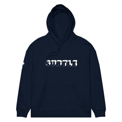 A navy blue hoodie with a front pocket and hood, featuring the word SUBTLE in bold white and gray 3D letters across the chest. A small Mambí graphic in white appears on the left sleeve.