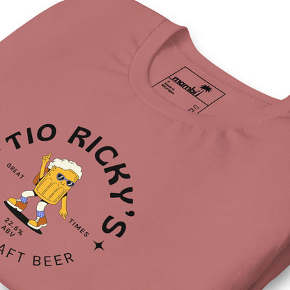 A pink t-shirt featuring a cartoon beer mug with sunglasses, arms, and legs holding up two fingers. The text reads Tio Rickys Craft Beer. Great Times. 2-8% ABV. Celebrate in Mambí style!.