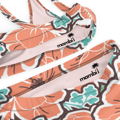 Close-up of the Printful Valeria High-Waisted Bikini Swimsuit for women, featuring orange, turquoise, and white hibiscus patterns. Includes removable pads and a small palm tree logo on the inside band.