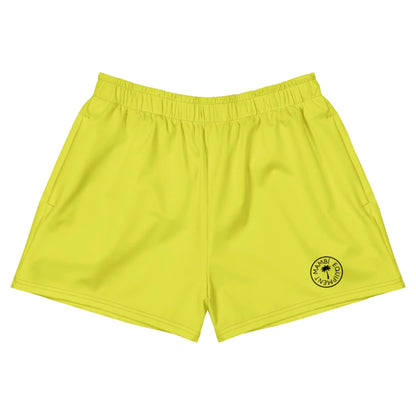 Bright yellow athletic shorts with an elastic waistband and a small circular black Mambí logo on the left leg featuring a star in the center. Shorts are laid flat on a white background.
