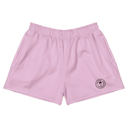 Light pink athletic shorts with an elastic waistband and a small circular black logo on the bottom left leg that reads MIAMI BEACH CLUB around a palm tree icon, featuring Mambí-inspired style. The shorts are laid flat on a white background.