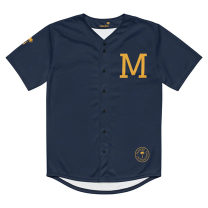 The Zoilo Classic Baseball Jersey by Printful features navy blue fabric with gold accents, a bold gold M on the left chest, a small circular logo at the hem, a functional gold emblem on the right sleeve, and black buttons. Unisex design.